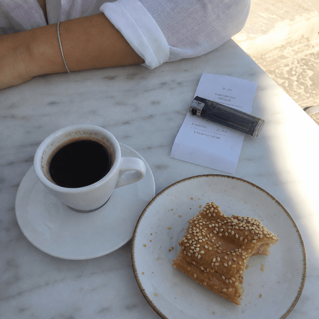 Un café noir, un koulouri entamé et un ticket sur une table en marbre.